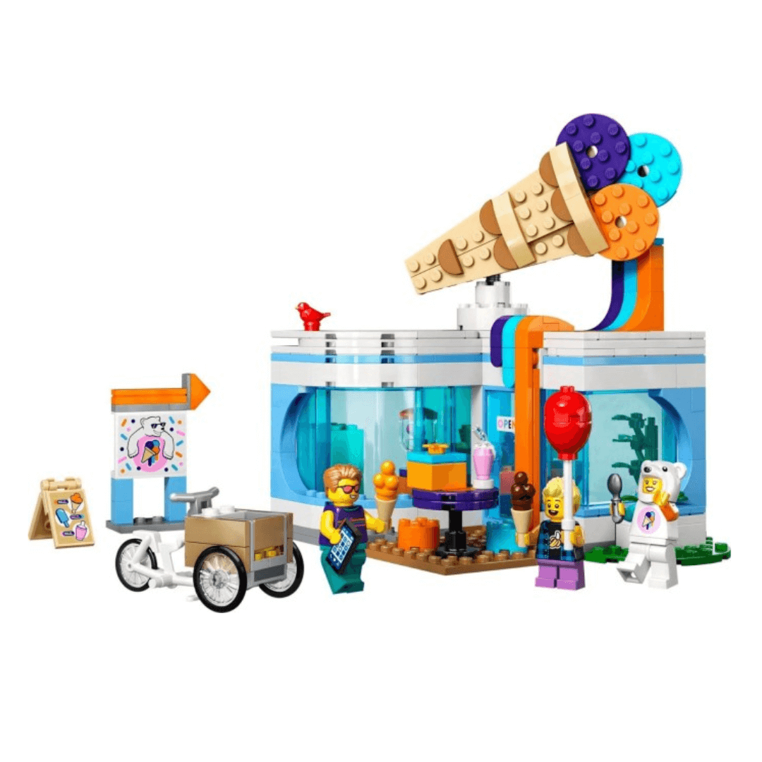 60363 Lego City Ice Cream Shop Built Set. Small Glass Building With IceCream Figure On Top Of Roof. An Icecream Bike Is Pictured With A Worker Figure. 2 Other characters Are Seen, One Holding An Icecream The Other Wearing A Polar Bear Costume Holding An Icecream Scoop.
