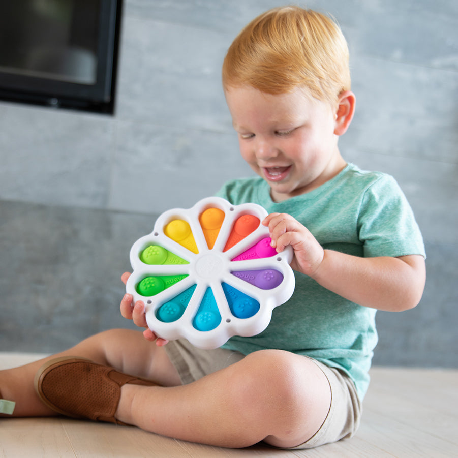 Child sitting and holding Fat Brain Toys Dimpl Digits 